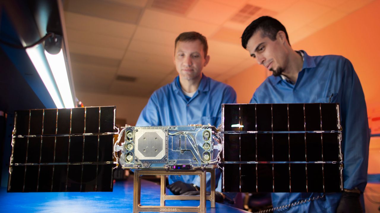 Engineers work on the assembly of the SunRISE space vehicle with the solar array deployed.