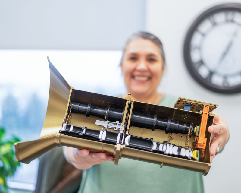 An SDL Outreach Coordinator shows the inside elements of the AWE Mission instrument model.