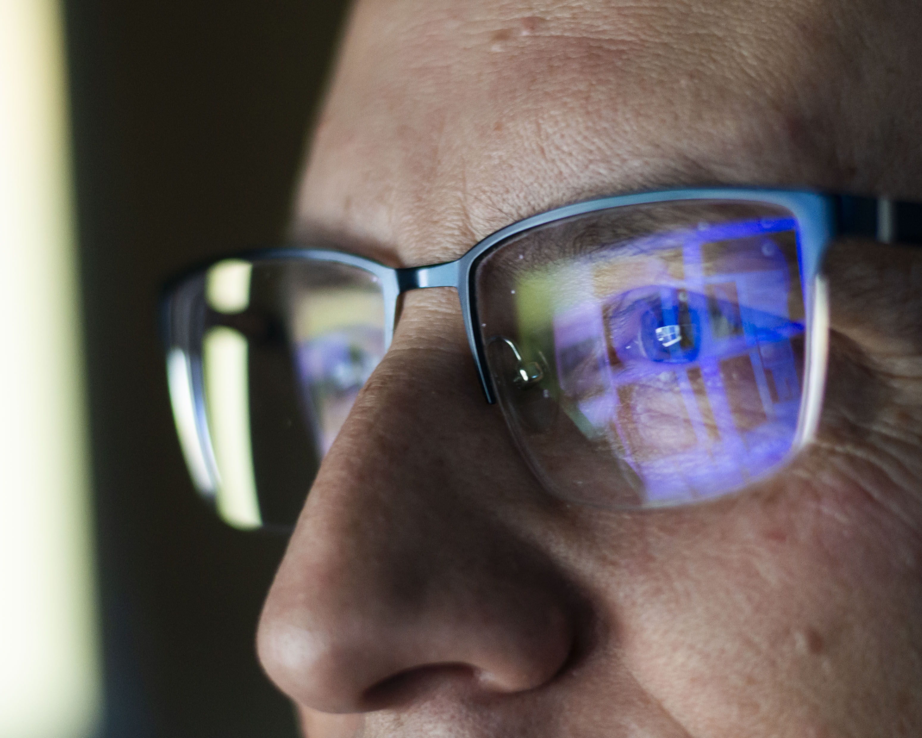 A close up of Pedro with computer screens reflected in his eye glasses.