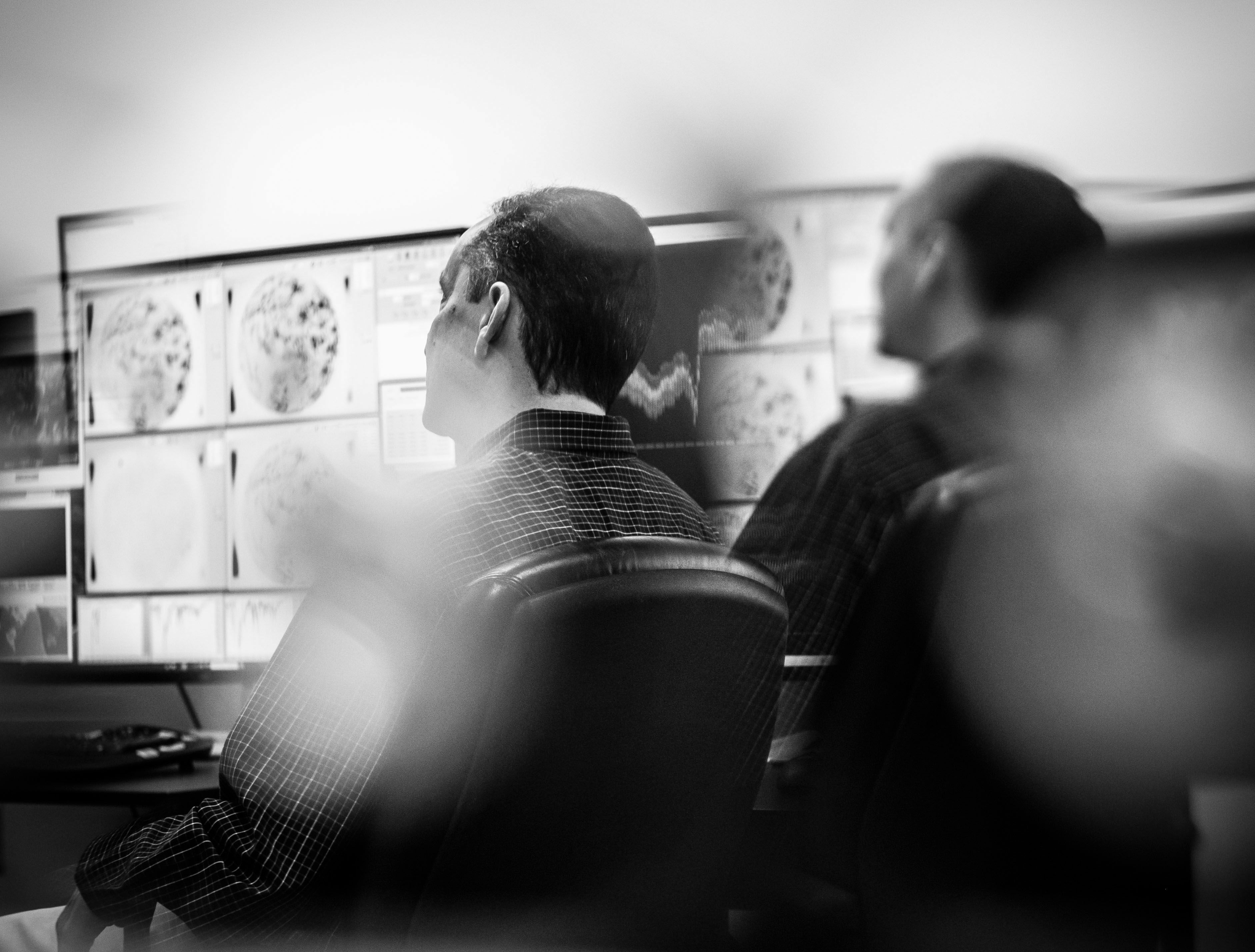 A black and white artistic expression of Pedro being interviewed in the AWE mission operations center.