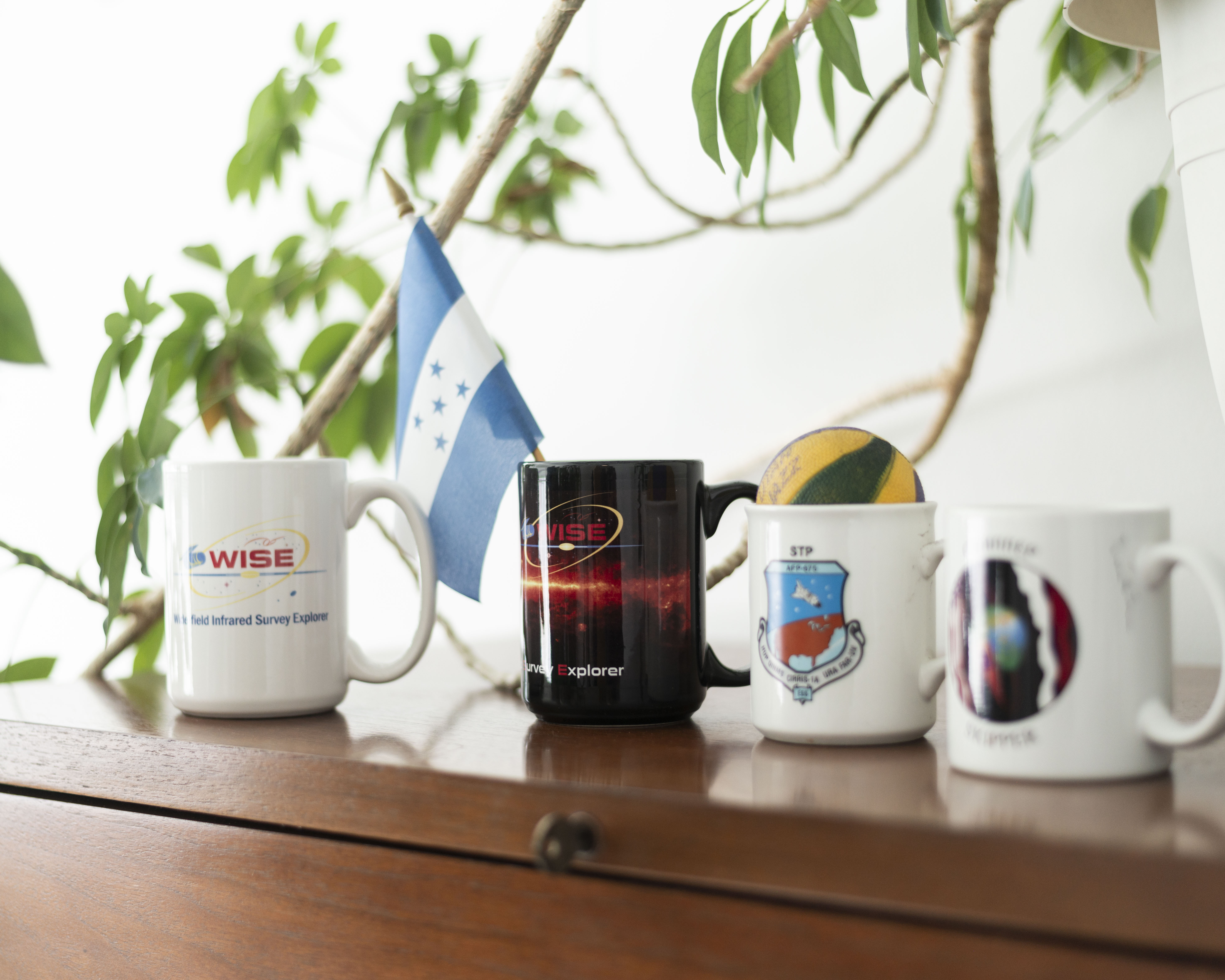 A collection of mission mugs and a small Honduran flag sit atop Pedro's book shelf.